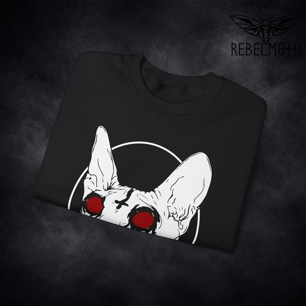 Close-up of sphynx cat red eyes and inverted cross print on black sweatshirt