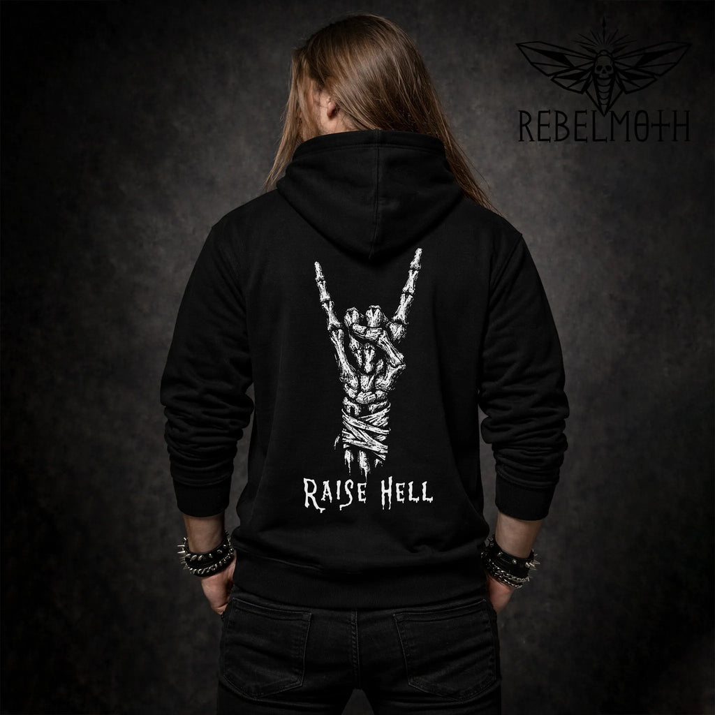 Man wearing a black hoodie with skeleton hand metal horns graphic and “RAISE HELL” text (devil horns back print hoodie)