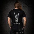 Back view of black t-shirt with skeleton hand throwing devil horns and Raise Hell text, worn by long-haired model with spiked bracelets and chain wallet